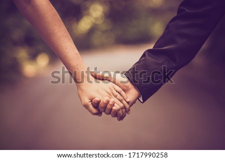 Wedding couple holding hands in sepia tone with path in background.