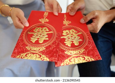 Wedding couple holding red envelope packet also known as hongbao. Chinese Wedding with Double Happiness Text Calligraphy Illustration on red packet. Soft focus image.