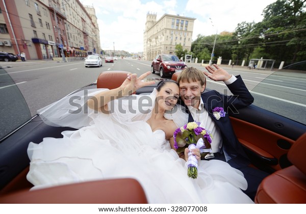 Wedding\
couple is hugging in a car. Beauty bride with groom. Beautiful\
model girl in white dress. Man in suit. Female and male portrait.\
Woman with lace veil. Cute lady and guy\
outdoors
