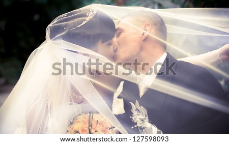 Wedding couple kissing covered veil