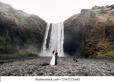 Wedding couple near Skogafoss waterfall. Destination Iceland wedding. The groom kisses the bride.