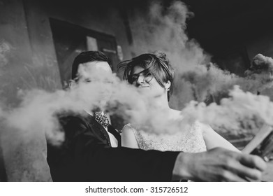 Wedding Couple Runs Color Smoke In The Park. Colour Bomb. Kiss And Hug