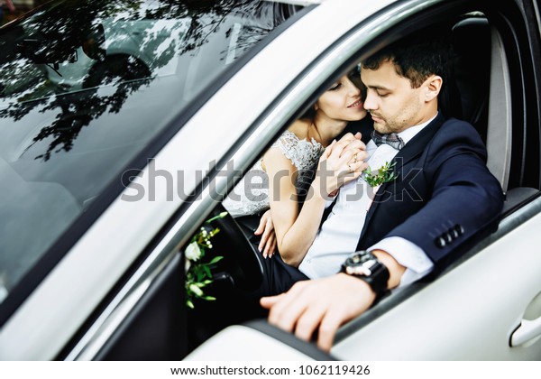 Wedding couple sitting and kissing in the car on\
their wedding day.