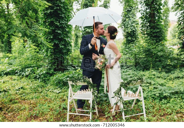 Wedding Couple Umbrella Kissing Near Decorative Stock Image