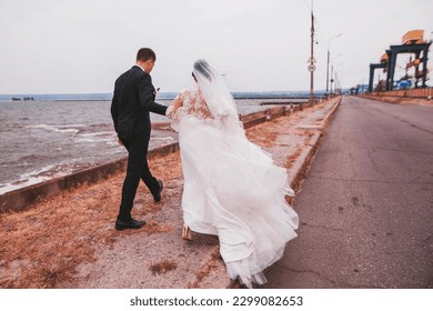 Wedding couple walking and hugging on the road near blue sea. Back view - Powered by Shutterstock