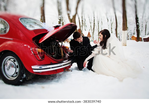 Wedding couple in\
winter near old vintage\
car