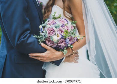wedding day, the bride and groom are holding a wedding bouquet, faces are not visible