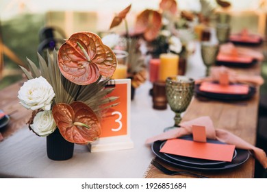 Wedding decor. Banquet. Glasses and plates, cutlery, candles and flower arrangements are on a wooden table in the garden