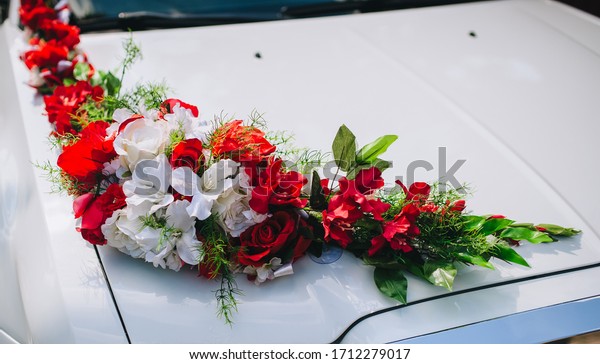 Wedding decoration made of\
artificial, paper flowers on a white car: roses, lilies.\
Photography, concept.