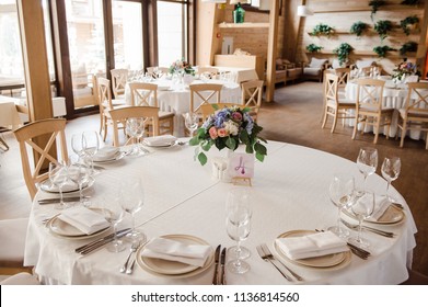 Wedding decorations. Decoration of the hall, restaurant. White tablecloth on Round table. Cutlery. Presidency of newlyweds. candles are burning. Flower compositions on table. Garland of light bulbs.