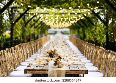 Wedding decorations. Served wedding table with golden plates, golden chairs, napkins, decorative fresh and dried flowers, candles and light bulbs. Celebration details, wedding outdoor	
