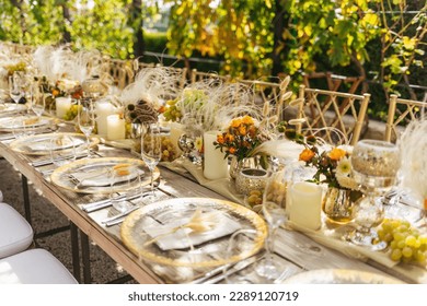 Wedding decorations. Served wedding table with golden plates, napkins, decorative fresh and dried flowers, candles and and light bulbs. Celebration details, wedding outdoor	
