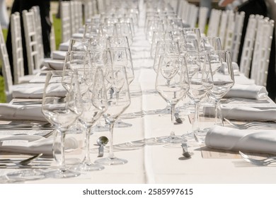 Wedding decorations. Served wedding table with plates, chairs, white napkins and wine glasses. Celebration details, outdoor wedding in garden during summer. Selective focus