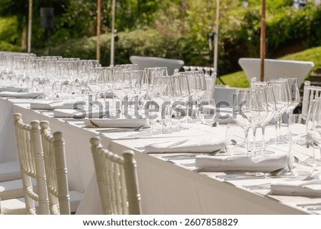 Wedding decorations. Served wedding table with plates, chairs, white napkins and wine glasses. Celebration details, outdoor wedding in garden during summer
