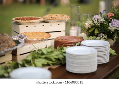 Wedding Dessert Bar With Cookies, Cakes, And Pies Rustic Wedding Decor Pink, Peach, Purple, And Green Floral Centerpieces On A Wooden Farm Table