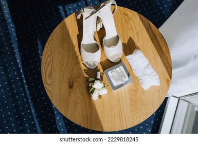 Wedding details, accessories close-up on a wooden table: shoes, rings, jewelry box, garter.