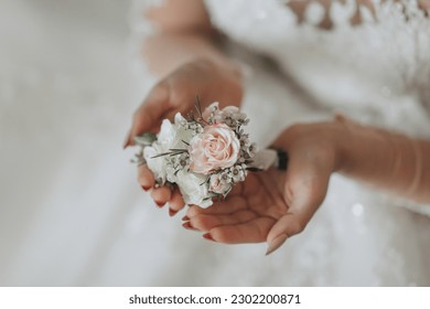 Wedding details. The bride holds the groom's wedding boutonniere. hands folded in the shape of a heart. Beautiful hands. French manicure