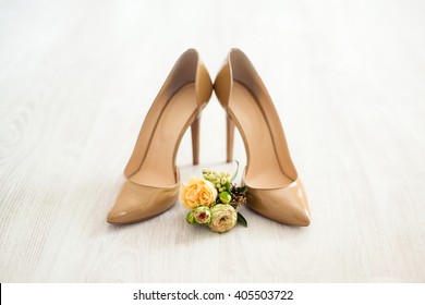 Wedding details, bride shoes, boutonniere. Beige patent leather shoes with heels.