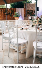Wedding dinner table reception. A close-up of the white classical chair for Chiawari's wedding, Tiffany near the round table, amid the lights of the garland