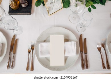 Wedding dinner table reception. The cream sheet of the menu is in a plate with a cloth napkin. Cutlery laid out according to the rules of etiquette. Top View 