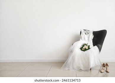 Wedding dress, bridal bouquet on grey chair and wedding shoes on floor in room - Powered by Shutterstock