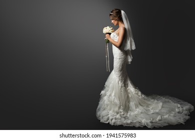 Wedding Dress. Bride in white Gown. Bridal Fashion Model holding Flower Bouquet. Profile View over Black Background. Copy space - Powered by Shutterstock