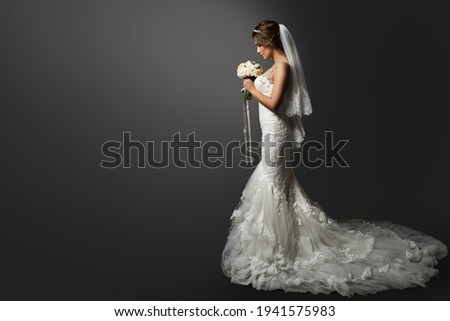 Wedding Dress. Bride in white Gown. Bridal Fashion Model holding Flower Bouquet. Profile View over Black Background. Copy space