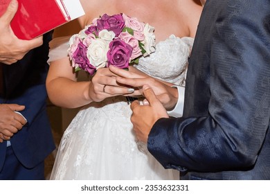 Wedding dress. Catholic wedding. Bridal bouquet. Bride and groom with their hands joined during the ceremony. - Powered by Shutterstock