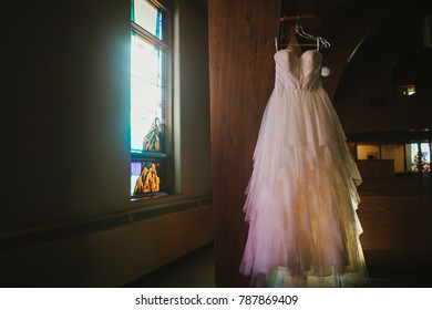 Wedding Dress Hanging By Stained Glass Window