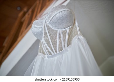 wedding dress hanging in the hotel. High angle view of a wedding dress hanging on a wooden ladder indoors. a white wedding dress hangs on a wooden ladder.