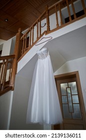 wedding dress hanging in the hotel. High angle view of a wedding dress hanging on a wooden ladder indoors. a white wedding dress hangs on a wooden ladder.