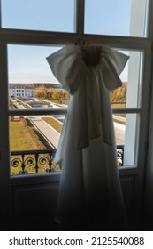 The Wedding Dress Is Hanging On A Hanger On An Ugly Background