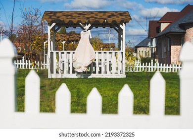 Wedding Dress Hanging On A Wooden Arbor.