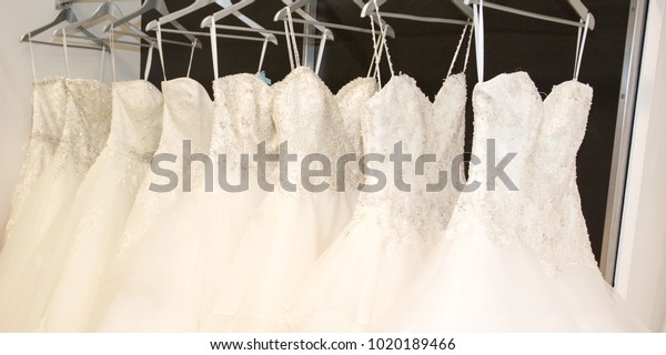 Wedding dresses hanging on a hanger. Fashion look\
in bridal salon