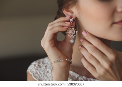 Wedding earrings on a female hand, she takes the earrings, the bride fees, morning bride, white dress, wear earrings