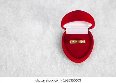 Wedding Gold Ring In A Red Heart Shape Box On A Snow. Top View. Text Space.