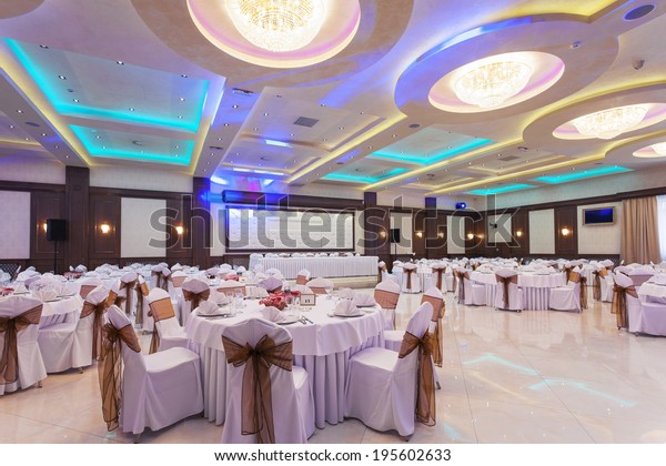 Wedding hall or other function facility\
with colorful ceiling lights set for fine dining\
