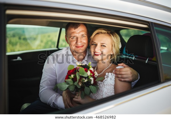 wedding: happy beautiful bride and groom in car\
with bridal bouquet hairstyle and bright makeup.  Concept of\
happiness and love.\
Newlywed