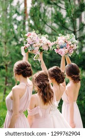 Wedding inspiration. Bridesmaids in rosy dresses holding wedding bouquets outdoor on green background. Happy summer wedding concept. 