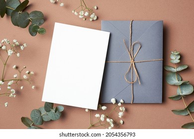 Wedding Invitation Or Greeting Card Mockup With Envelope And Eucalyptus And Gypsophila Twigs On Paper Background.