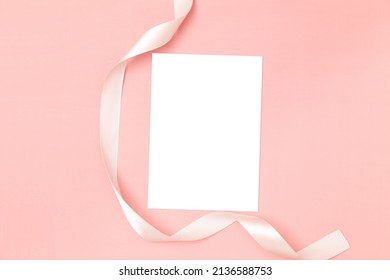 Wedding Invitation Or Greeting Card Mockup. Blank White Card 5x7 With White Satin Ribbon On Pink Background.