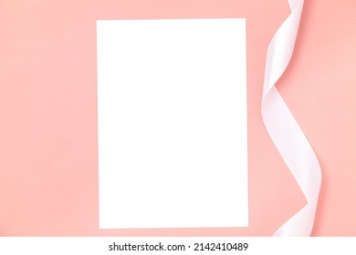 Wedding Invitation Or Greeting Card Mockup. Blank White Card 5x7 With A White Satin Ribbon On A Pink Background.