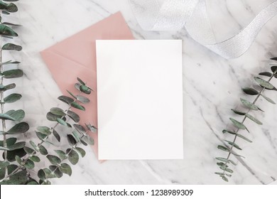 Wedding invitation mockup card with paper and envelope, roses, gifts, Eucalyptus, ribbon on marble background, top view, flat lay - Shutterstock ID 1238989309