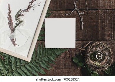 wedding invitation mock-up and rustic boutonniere and wedding rings in bird nest on wooden  background with fern leaves. rustic barn wedding concept. top view. flat lay, empty card - Powered by Shutterstock