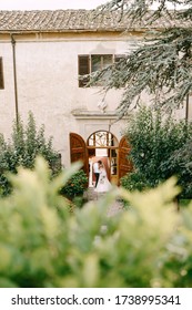 Wedding At An Old Winery Villa In Tuscany, Italy. A Wedding Couple Is Standing Near The Old Wooden Doors In The Villa-winery.