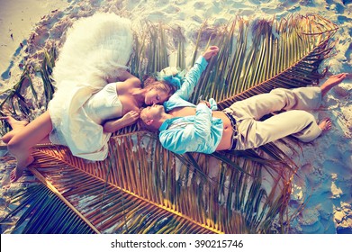 Wedding on the beach . Young beautiful couple  in wedding dress  lying on a palm leaf in the beach  on a tropical island . Happy newlyweds . Romantic beautiful wedding