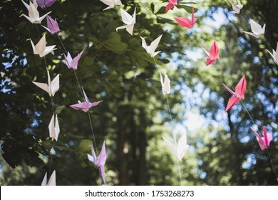 Wedding outdoor summer decoration between treees. Sunny day. Origami birds flying in the wind