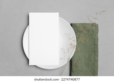 Wedding paper blank menu card mockup on white plate with botanical decor, mockup with copy space, top view