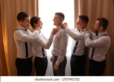 Wedding photo about helping of the groomsmen to the groom at wedding day, they put on a bow tie