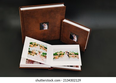 Wedding Photobooks In Brown Leather Binding With Photos On The Cover. High-quality And Expensive Photo And Printing Products. Services Of A Professional Photographer And Designer. On Black Background